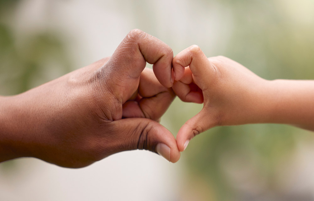 a child hand and adult hand forming a heart