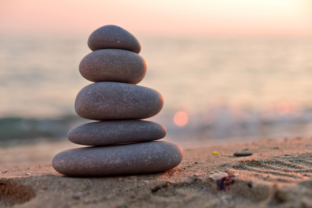a stack of stones in the sand on a beach at sunset